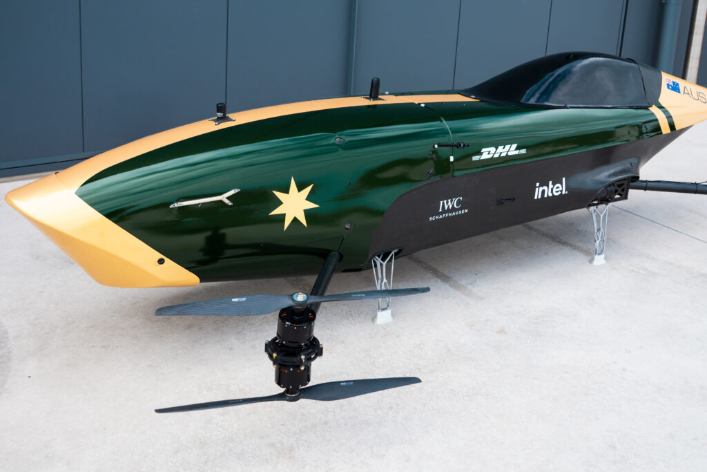 Green-and-yellow hydroplane race boat on a stand, displaying DHL and Intel logos and Australian flag.