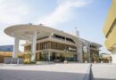 Exterior view of a modern Skyports building with a curved white canopy, tall pillars, and a paved plaza.