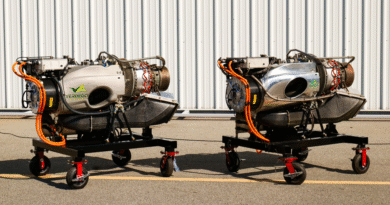 Two small jet engines on mobile stands side by side in a hangar, with orange hoses and a corrugated metal wall behind them (VERDEGO branding).