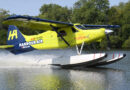 Colorful seaplane taking off from water, bright yellow and blue Harbour Air aircraft lifting above the surface.