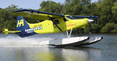 Colorful seaplane taking off from water, bright yellow and blue Harbour Air aircraft lifting above the surface.