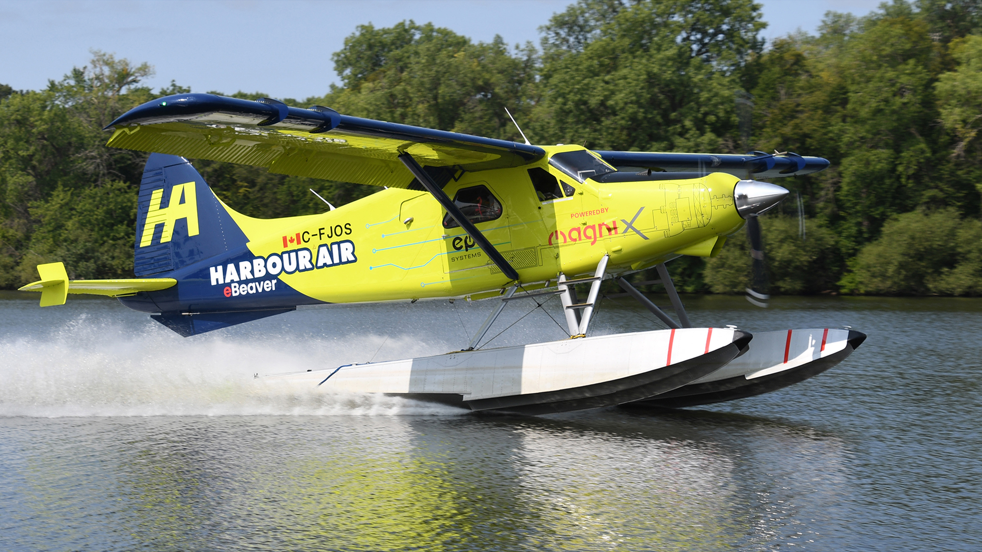 Colorful seaplane taking off from water, bright yellow and blue Harbour Air aircraft lifting above the surface.