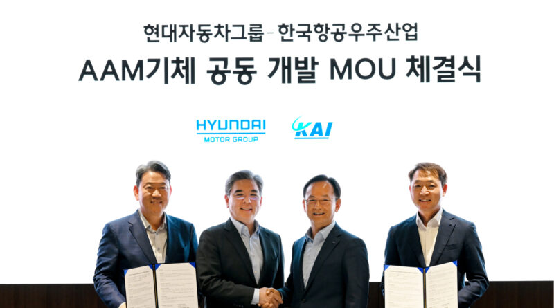 99fb0d9e63634ab7a02829595354ac3a - eVTOL Insights Four executives in suits celebrate a MOA signing between Hyundai Motor Group and KAI, holding signed documents under a Korean banner and logos above.