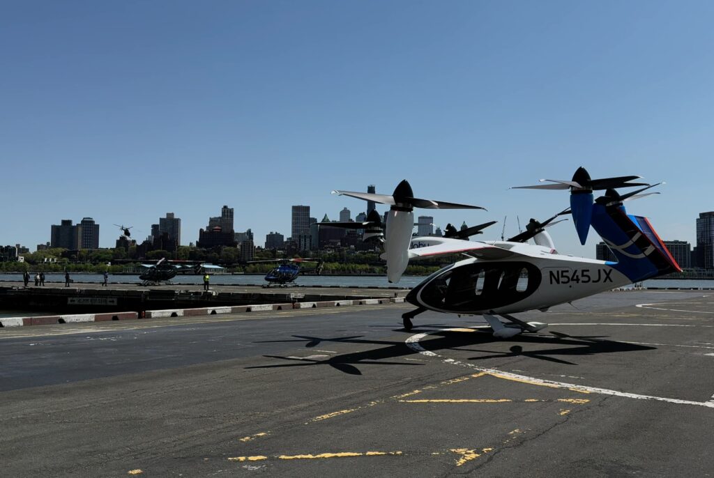 Seaplanes with large propellers parked on a runway in front of a city skyline under a clear blue sky.