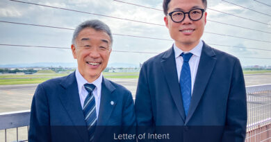 ENSkyDrive-and-Tohoku-Air-Service - eVTOL Insights Two men in suits smiling on a rooftop at an airfield, announcing a partnership between Tohoku Air Service and SkyDrive.