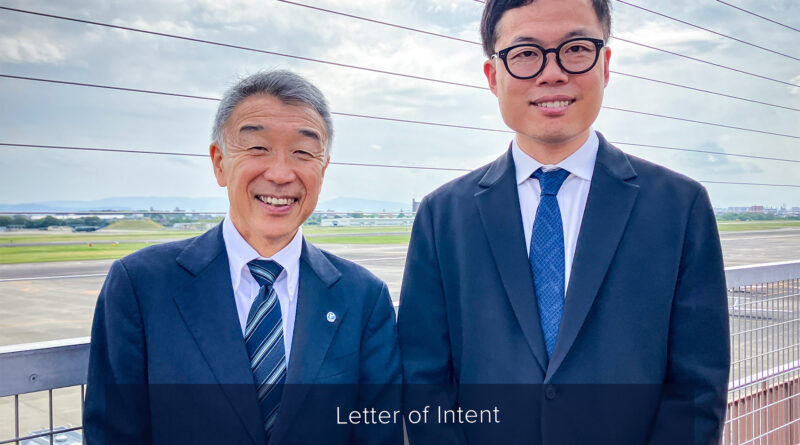 ENSkyDrive-and-Tohoku-Air-Service - eVTOL Insights Two men in suits smiling on a rooftop at an airfield, announcing a partnership between Tohoku Air Service and SkyDrive.