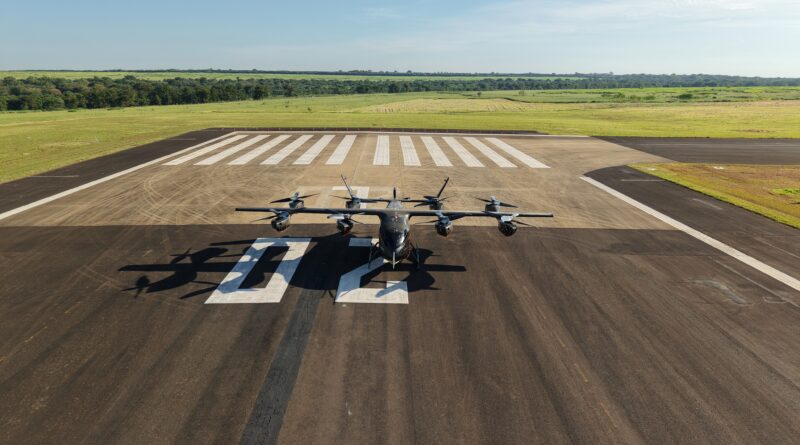 Small propeller aircraft parked on a runway with white striped markings and open fields beyond. (informative)