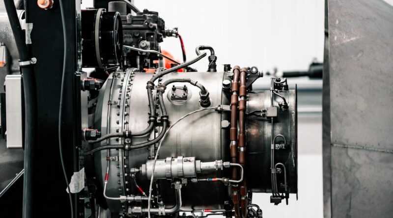 Close-up of an industrial engine with hoses, pipes, and metallic components in a mechanical setup.