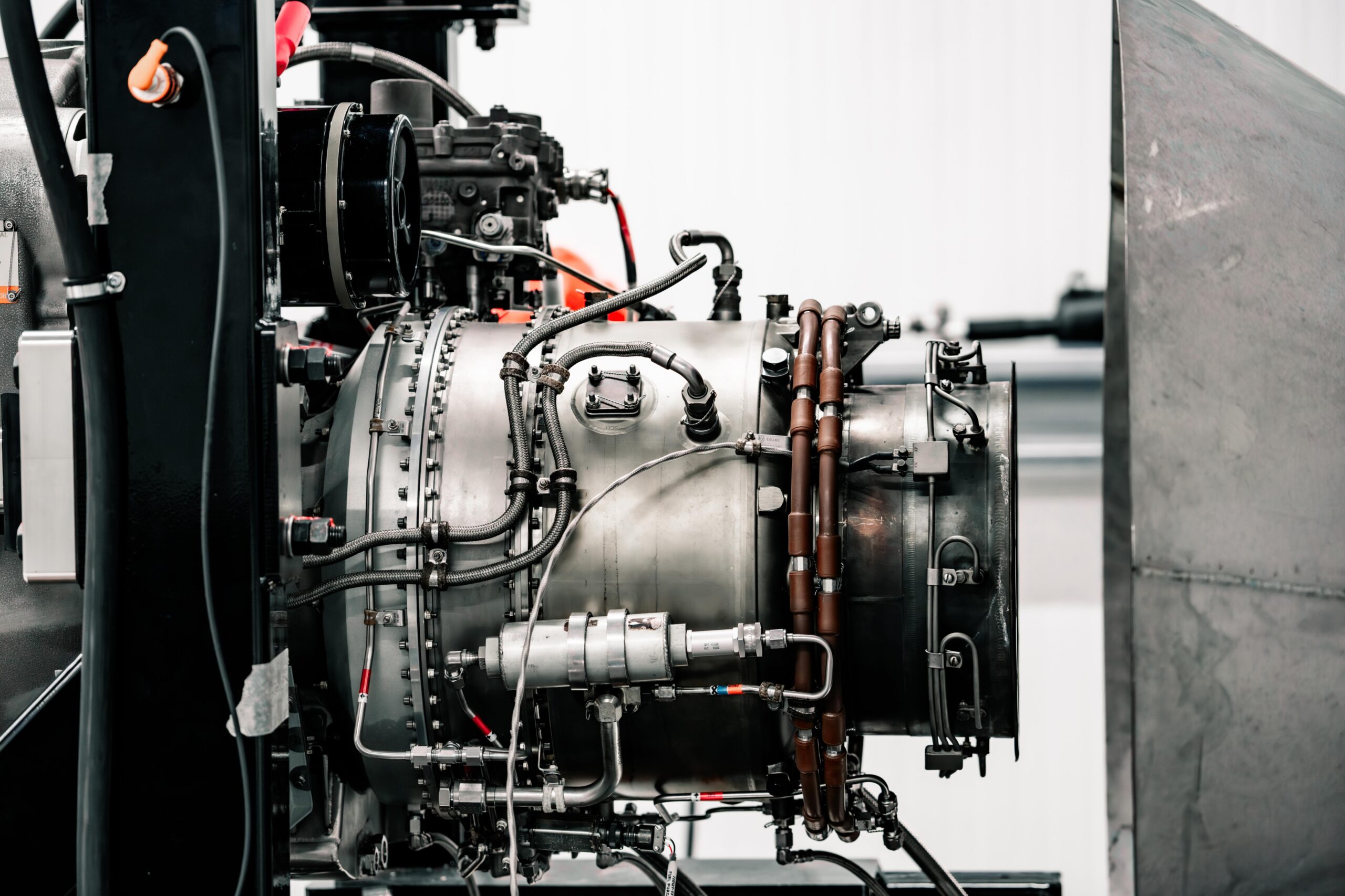 Close-up of an industrial engine with hoses, pipes, and metallic components in a mechanical setup.