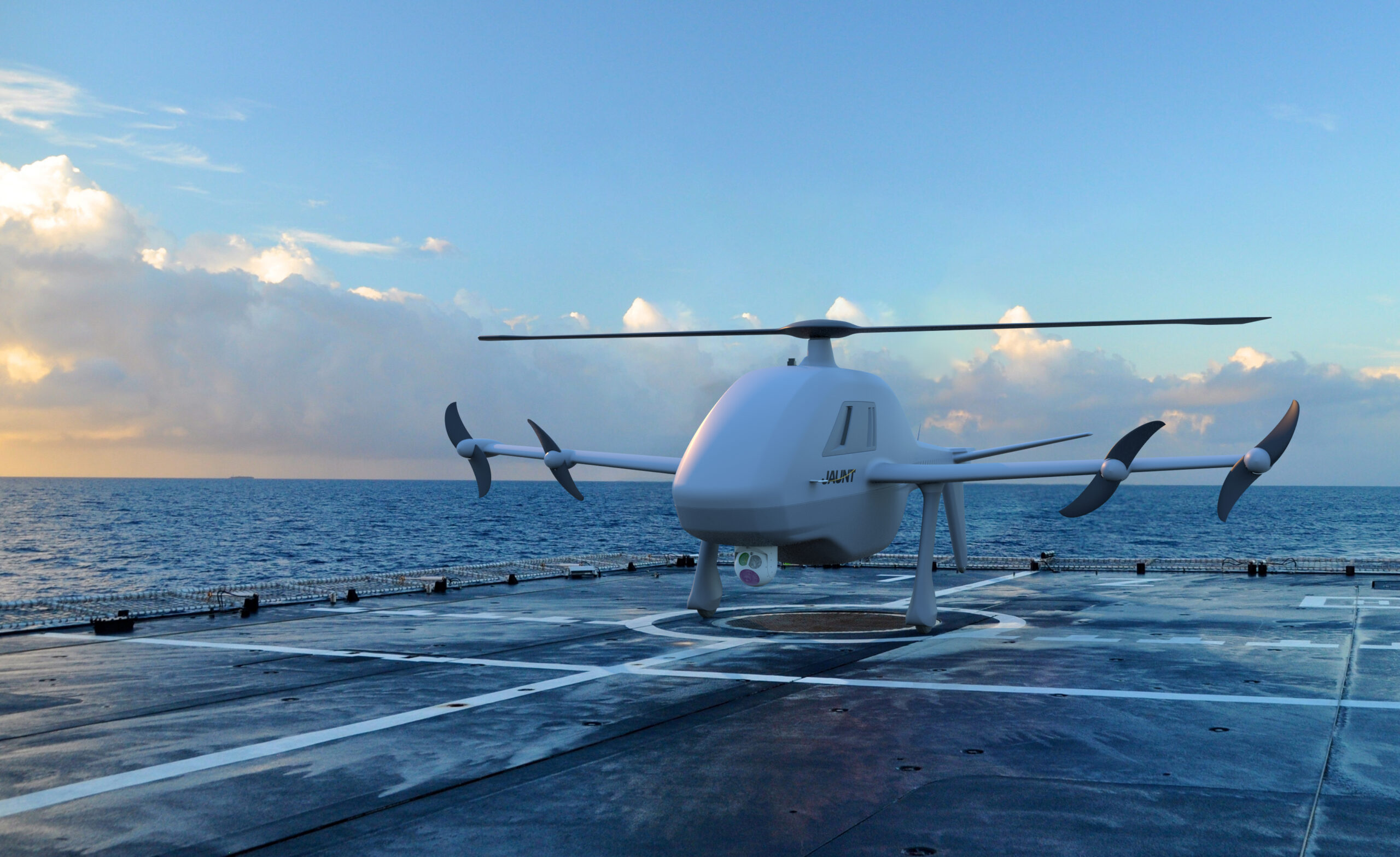 White quadcopter drone on a windswept deck with the ocean and cloudy sky in the background.