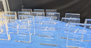A row of blue glass awards labeled WINNER on a blue table at an awards ceremony display area.