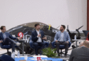 Panel discussion in an aircraft hangar with four speakers seated and a small airplane behind them.