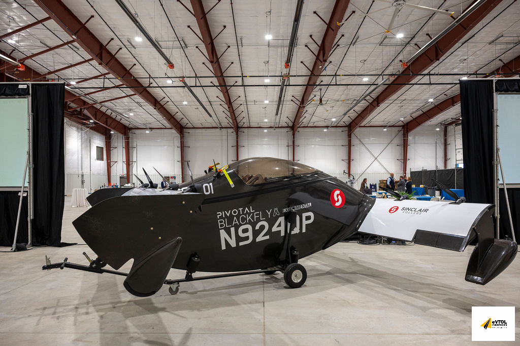 Black experimental aircraft with registration N924P parked in a hangar, showing 'Pivotal Blackfly' and Sinclair College logos on the fuselage.