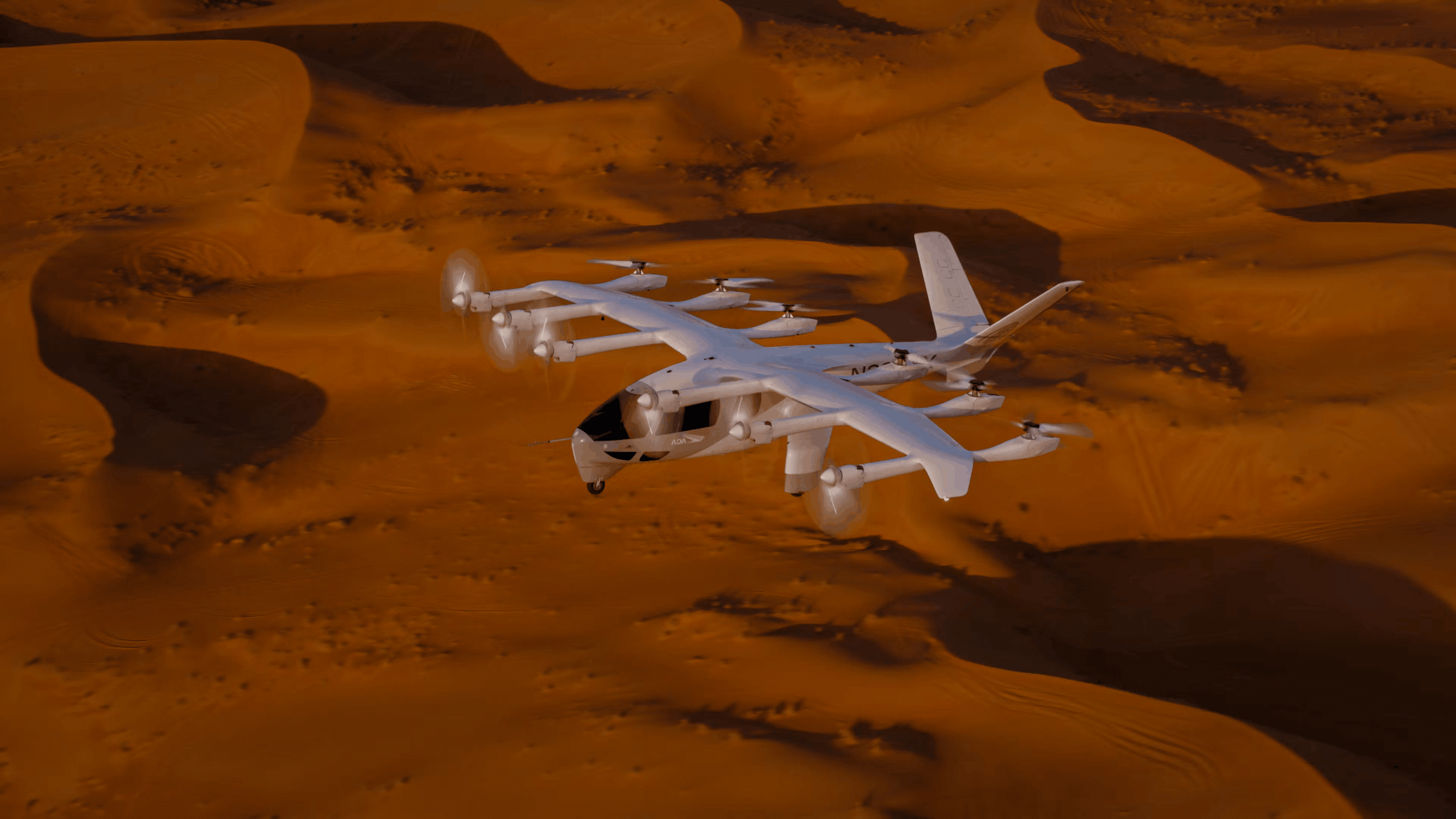 White tilt-rotor aircraft flying low over orange desert sand dunes.