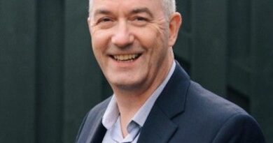 Richard Alexander - eVTOL Insights Smiling man with short gray hair in a blazer and light shirt, outdoors against a dark fence backdrop.