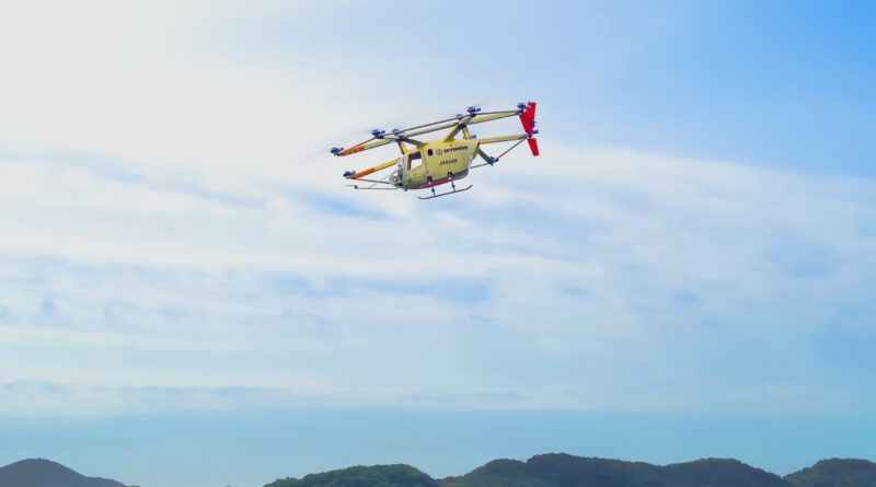 260622_高速飛行_プレスリリース用画像_final_文字無し-2048x1152 - eVTOL Insights Yellow helicopter in midair above a ridge of green hills, against a clear blue sky.