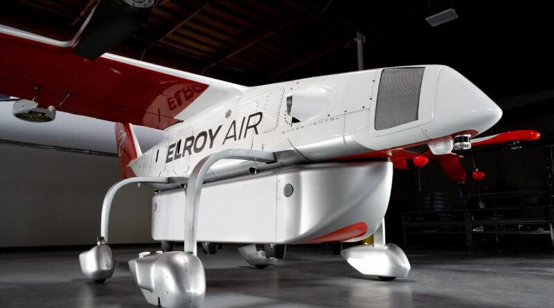 White and red Elroy Air experimental aircraft indoors, shown from the side with visible landing gear and tail section.