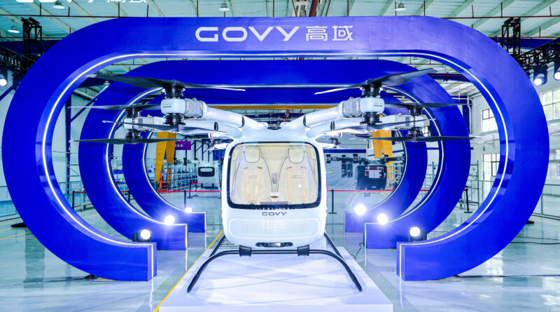 Front view of a white Govy helicopter displayed inside a large blue circular structure at an exhibition hall.