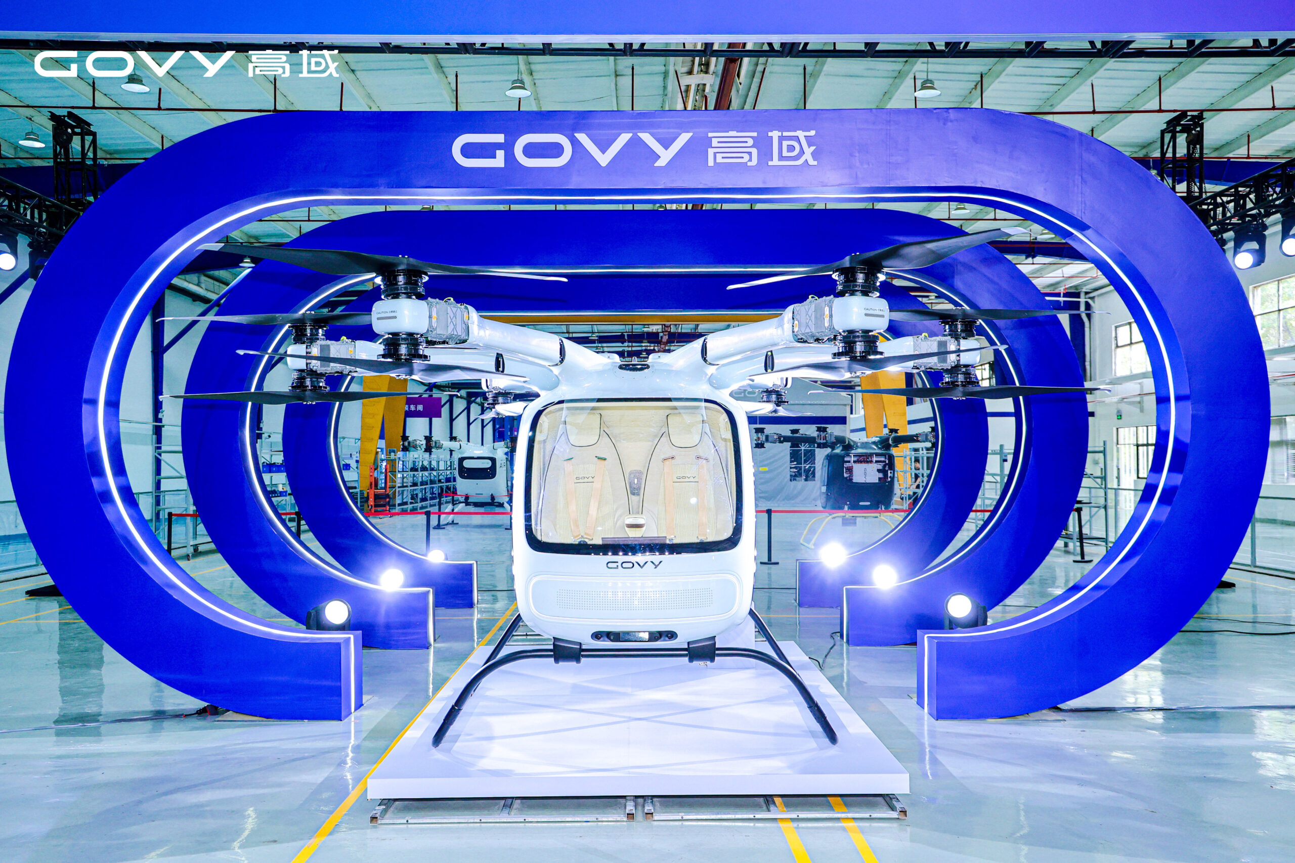 Front view of a white Govy helicopter displayed inside a large blue circular structure at an exhibition hall.