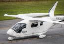 White small aircraft on a runway with two pilots visible in the cockpit and tail number N916LF on the fuselage.
