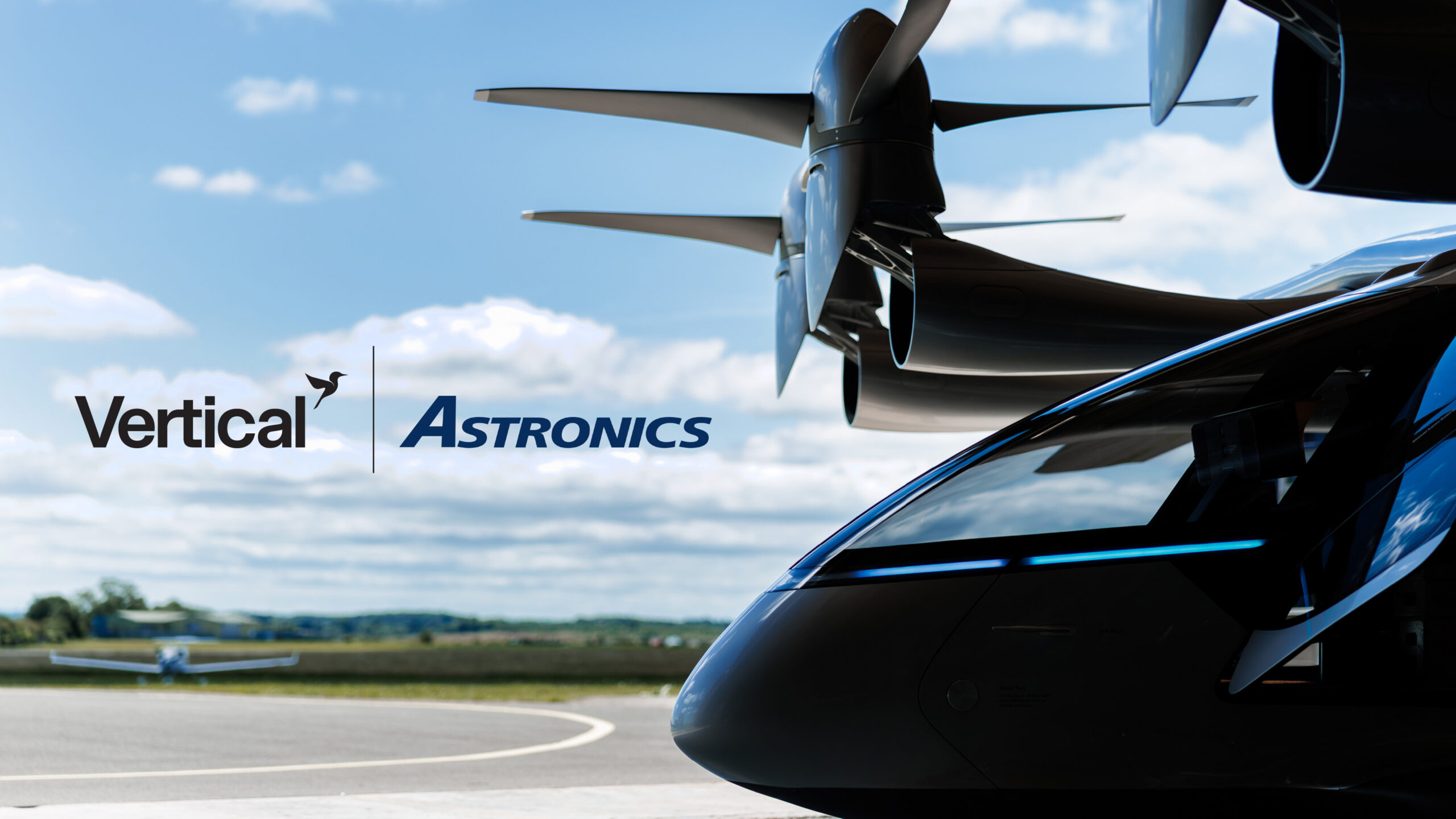Close-up of a helicopter nose with rotor hub above and the Vertical Astronics logo on the fuselage against a blue sky.