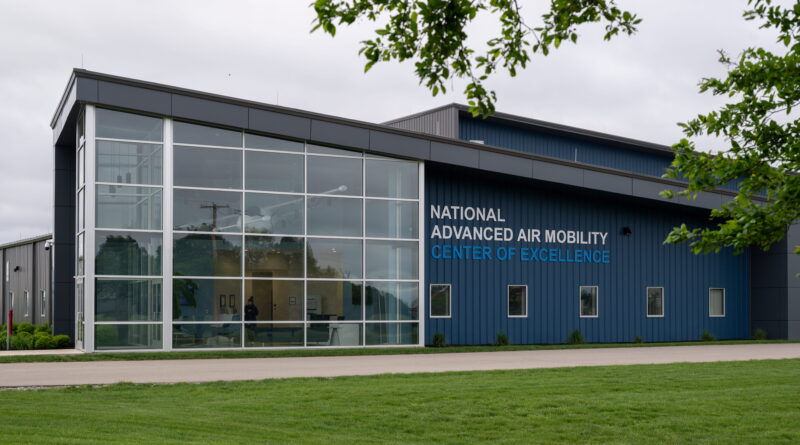 Modern blue building with large glass entrance and a sign reading 'NATIONAL ADVANCED AIR MOBILITY CENTER OF EXCELLENCE'.
