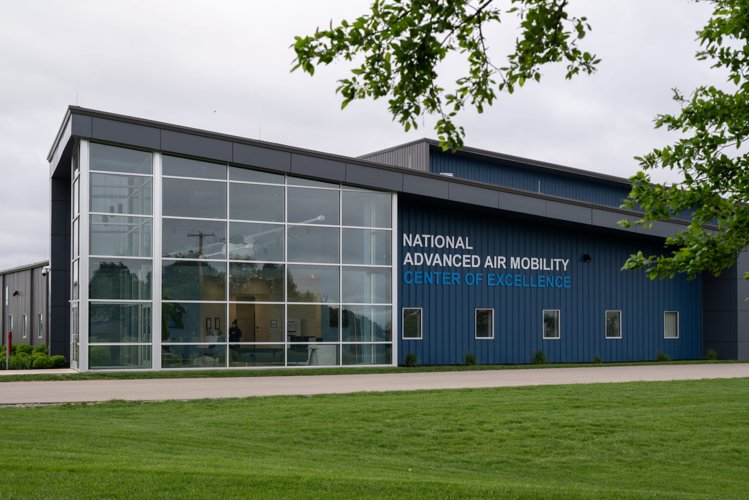 Modern blue building with large glass entrance and a sign reading 'NATIONAL ADVANCED AIR MOBILITY CENTER OF EXCELLENCE'.