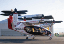 f6f56b30e34087cec9a6da96df82f4fdc7c97874-6000x4000 - eVTOL Insights Tilt-rotor aircraft on the ground with rotors folded, branded Toyota and Joby, at an airfield.