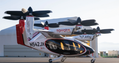 Tilt-rotor aircraft on the ground with rotors folded, branded Toyota and Joby, at an airfield.