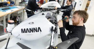 manna-team - eVTOL Insights Engineer tightens a component on a white drone-like aircraft labeled MANNÁ in a bright workshop.