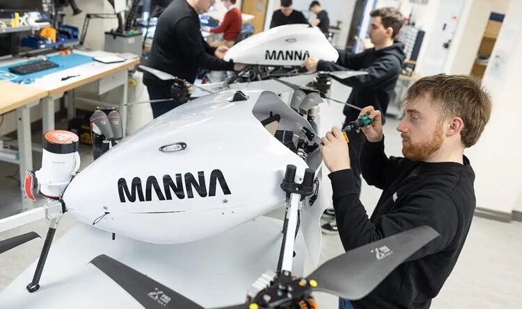 manna-team - eVTOL Insights Engineer tightens a component on a white drone-like aircraft labeled MANNÁ in a bright workshop.