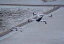Three light aircraft in formation over a cracked salt flat landscape.
