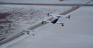 Three light aircraft in formation over a cracked salt flat landscape.