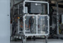 unnamed 53 - eVTOL Insights Wheeled metal-frame equipment cart with a glass enclosure containing electrical components and a tangle of cables in a laboratory.