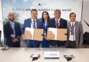 2 - eVTOL Insights Five professionals in business attire stand behind a table holding large folders, posing for a group photo at an aviation event.
