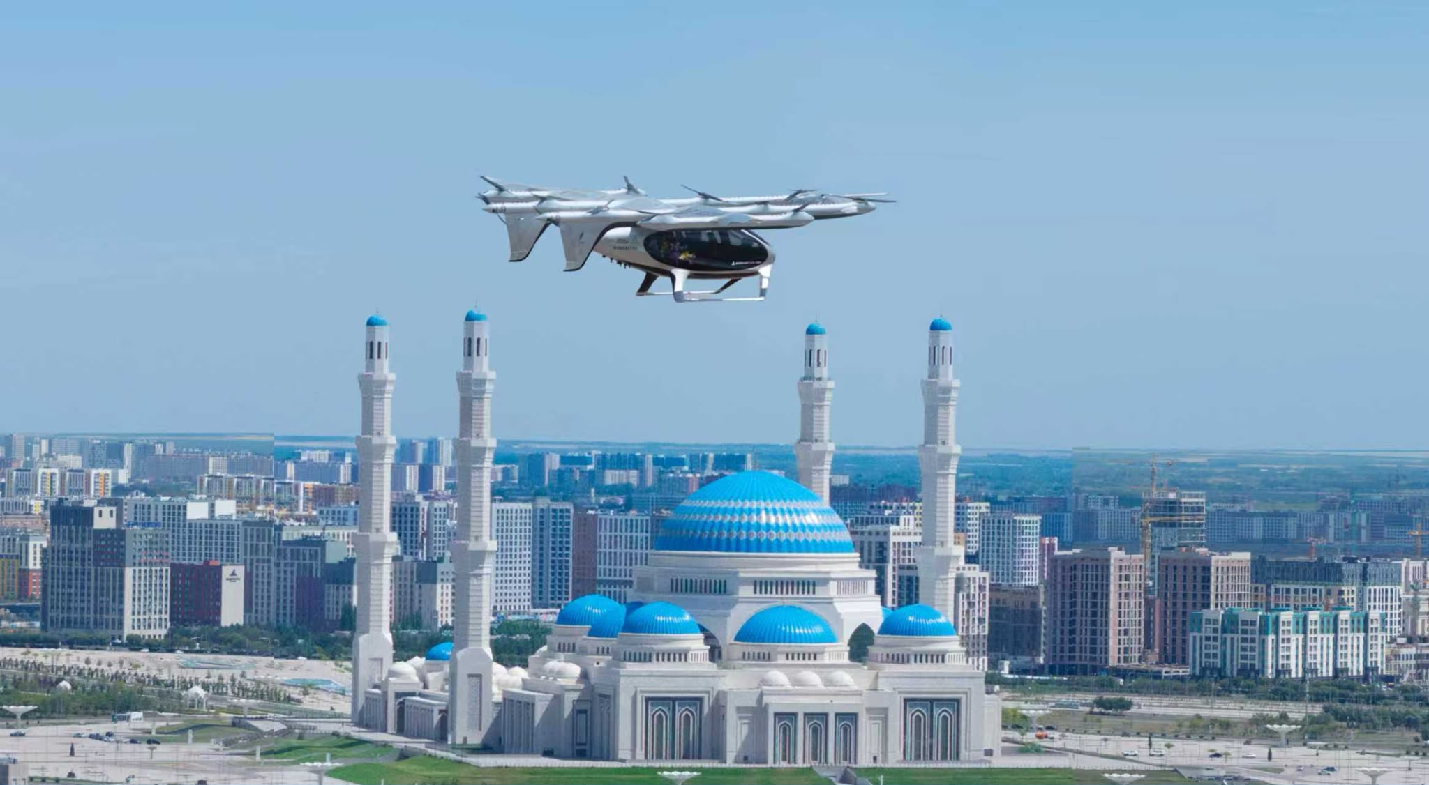 Autonomous aerial drone flying over a city with blue-domed mosques and tall minarets at sunset.",