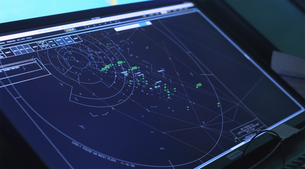 High-tech radar display with concentric circles, gridlines, and green telemetry points on a dark screen.