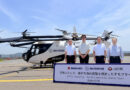 Four men in white shirts stand beside a SkyDrive eVTOL helicopter on a runway, with a promotional sign in front about Seto Inland Sea tours (dated 2026-07-13).