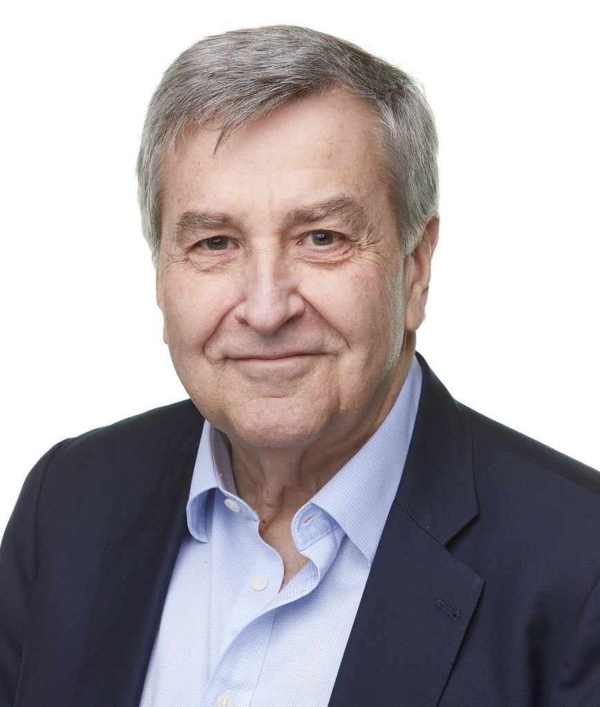 Portrait of a smiling senior man in a navy blazer and light blue shirt