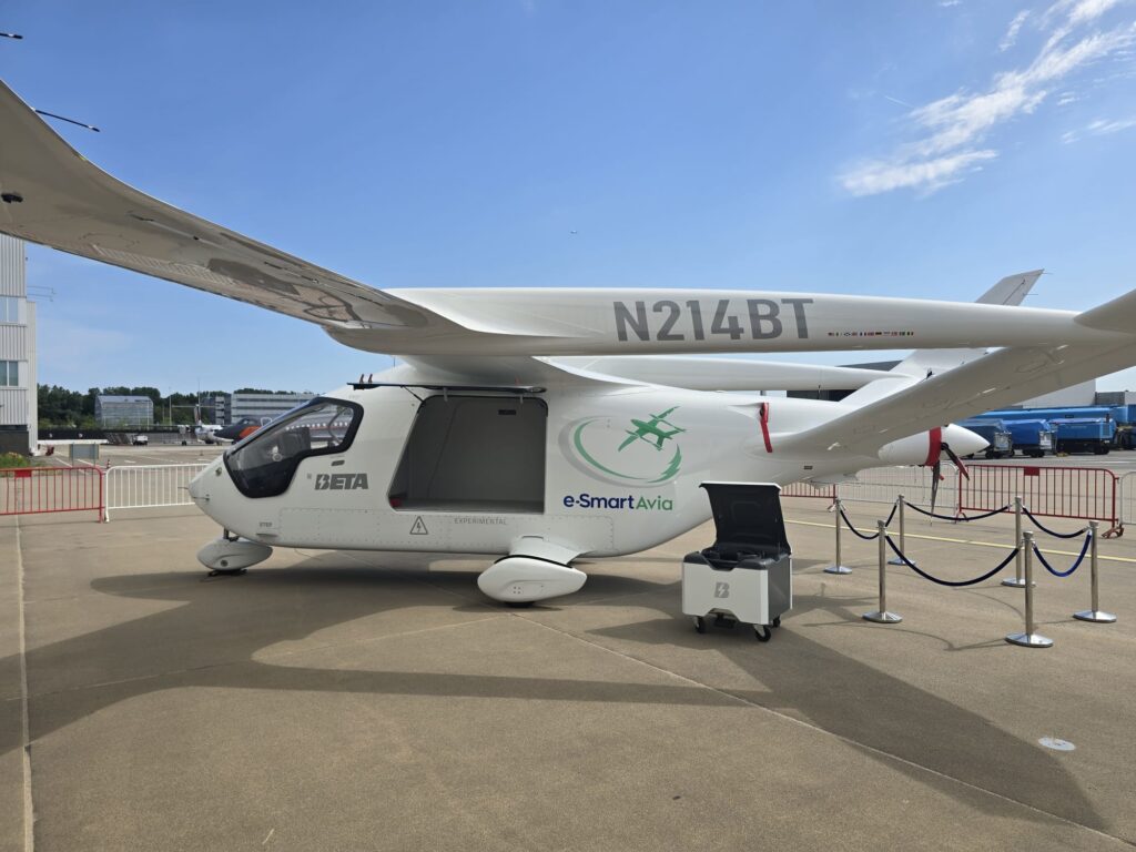 White experimental aircraft on display at a airport tarmac, registration N214BT, with e-SmartAvia branding on the fuselage.