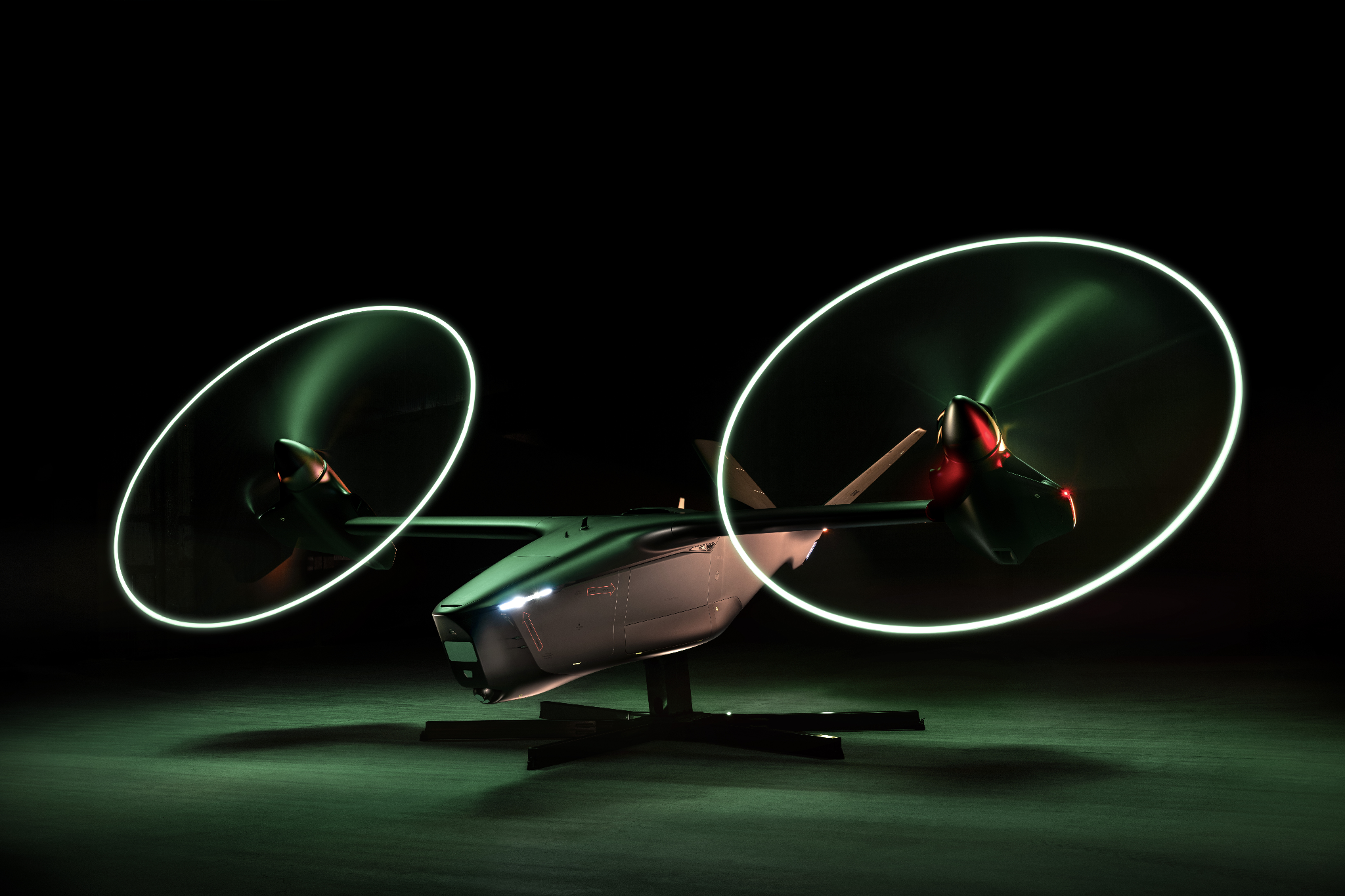 Futuristic aircraft on a stand at night with neon green propeller rings in motion.