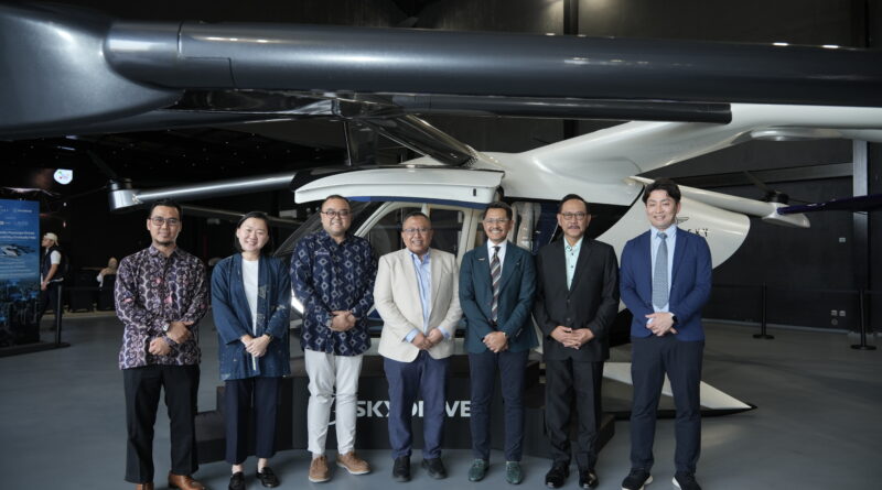 Group of professionals posing in front of a large helicopter inside a showroom or exhibit hall.