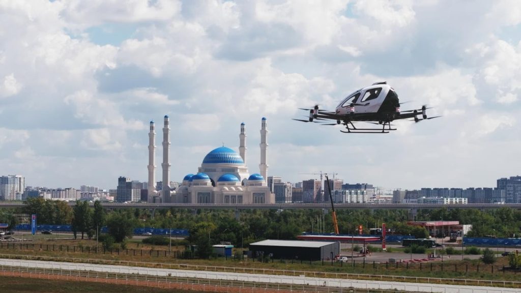 EH216-S 2 - eVTOL Insights Drone flying over a cityscape with a blue-domed mosque and tall minarets in the background.