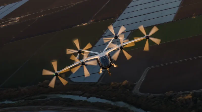 Six-propeller fixed-wing drone flying over farmland, sunlight glinting on the fuselage and wings.