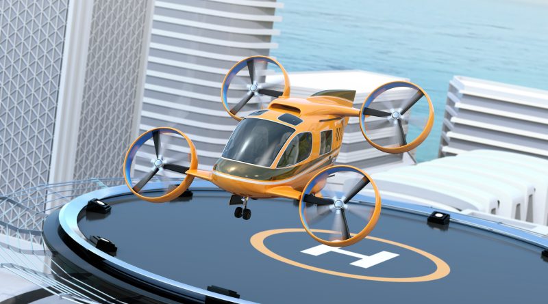 Orange quadcopter drone perched on a circular rooftop landing pad with a cityscape and ocean in the background