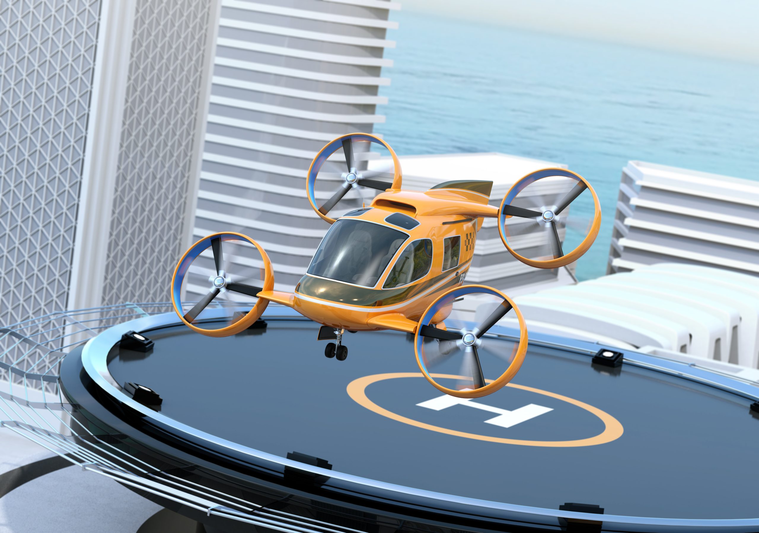 Orange quadcopter drone perched on a circular rooftop landing pad with a cityscape and ocean in the background